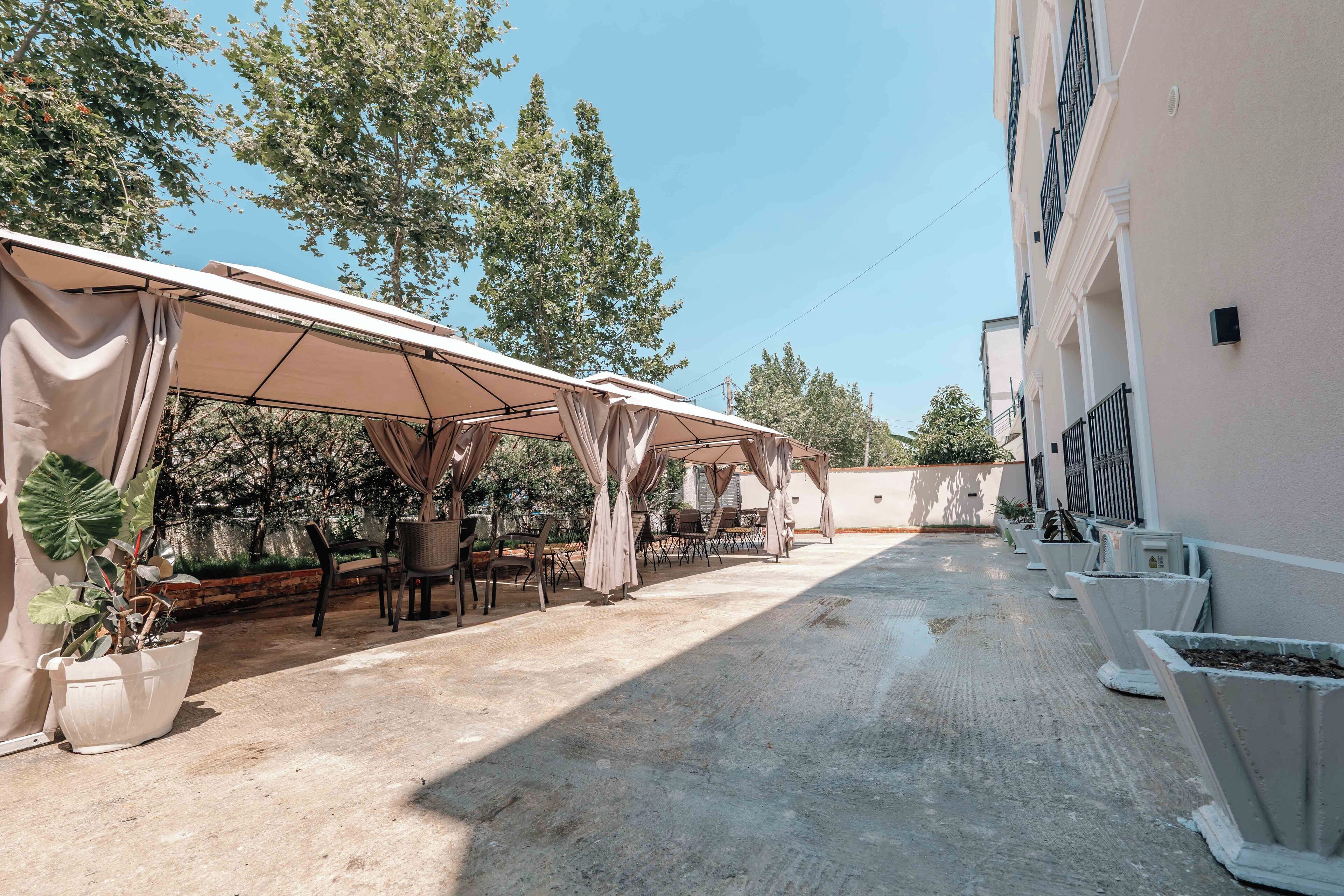 An outdoor patio area with covered seating and potted plants.