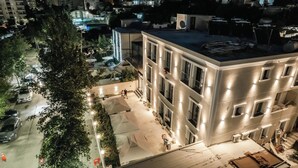 Un immeuble à plusieurs étages avec une cour intérieure, entouré d’arbres et de voitures garées.