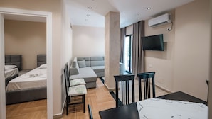 Une chambre d’hôtel moderne dotée d’un coin repas, d’un canapé et d’un téléviseur fixé au mur.