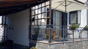A house with a covered porch, a small balcony with a railing, and potted plants. - Mary House (Scauri)