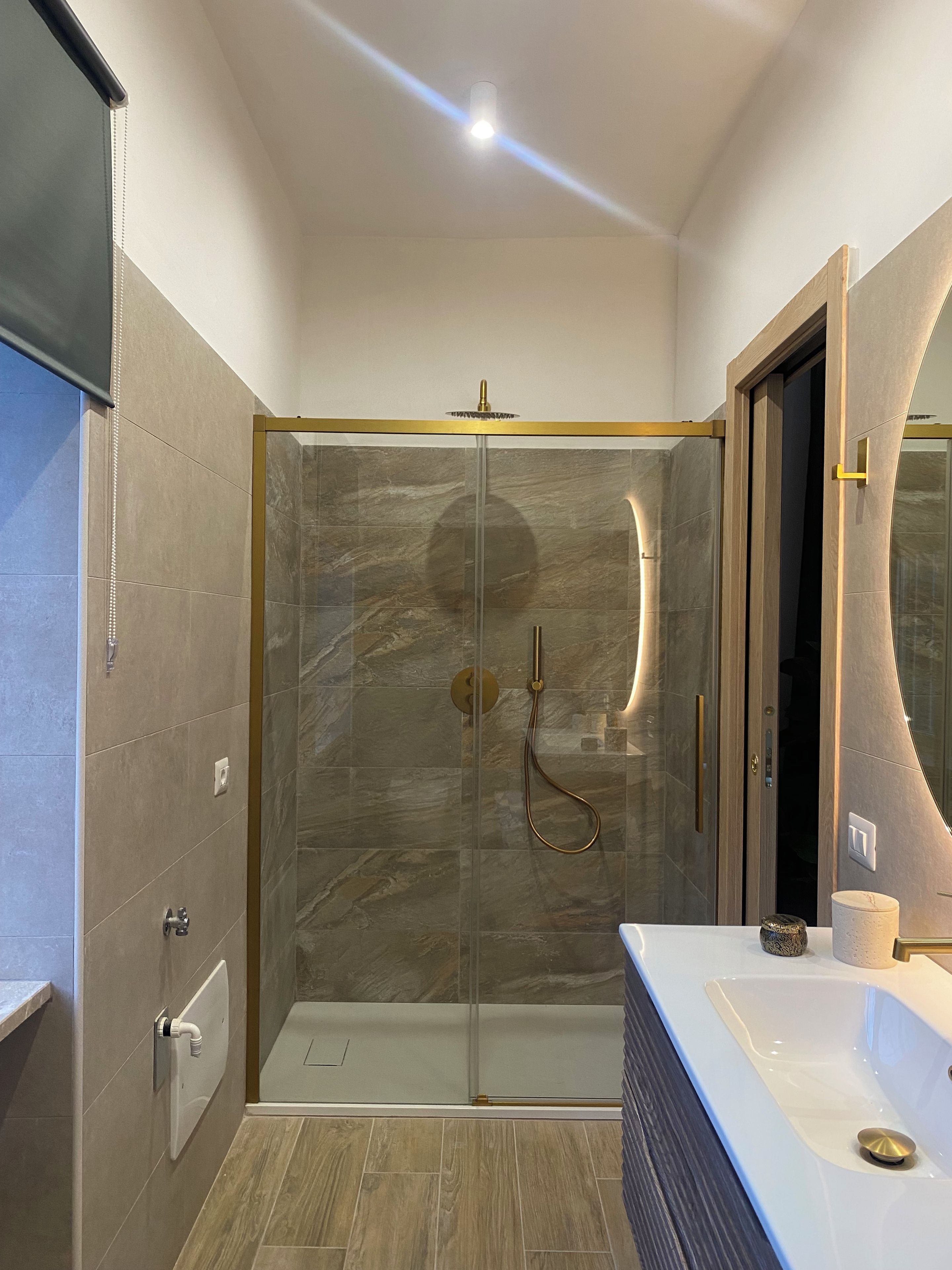 A modern bathroom with a glass-enclosed shower, a vanity with a large mirror, and a bathtub.