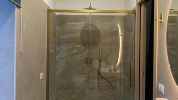 A modern bathroom with a glass-enclosed shower, a vanity with a large mirror, and a bathtub.