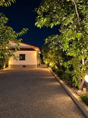 A paved driveway leading to a building with a stone foundation and a tiled roof.