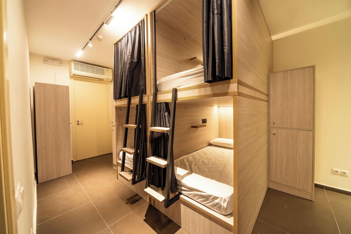 Une petite pièce avec des lits superposés, une armoire et une petite étagère.