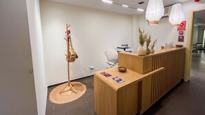 Un comptoir d’accueil avec un revêtement en bois, un tapis tissé et un porte-manteau avec un sac.