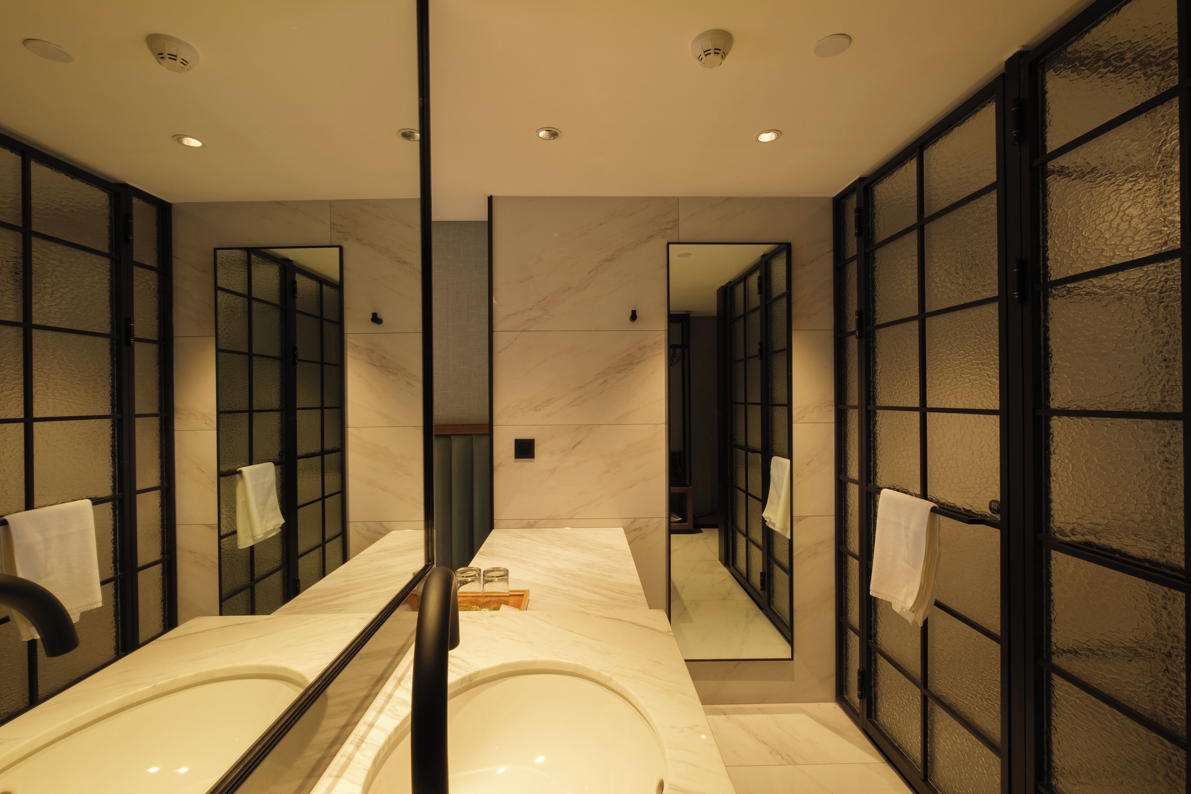 A modern bathroom with a large mirror, a bathtub, and a glass partition.