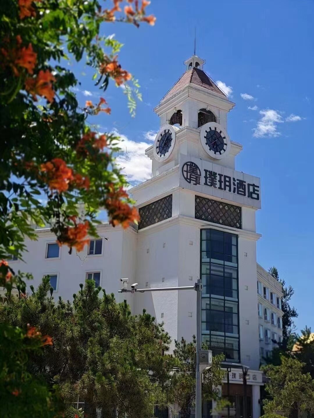 A hotel with a clock tower, large windows, and a sign in a foreign language.