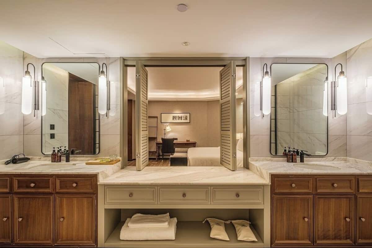 Un baño moderno con lavamanos doble, armarios de madera y un espejo.