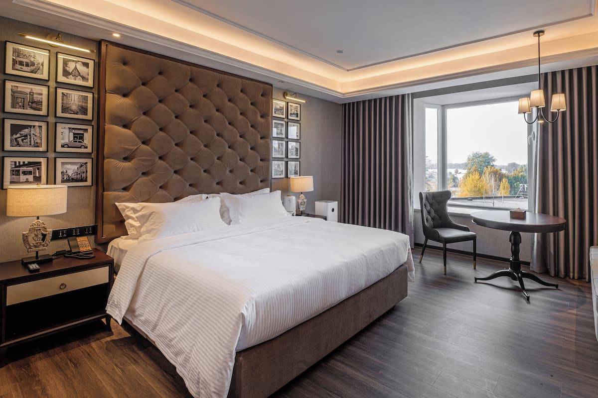 Habitación de hotel con una cama grande, un escritorio, una silla y vistas al exterior.