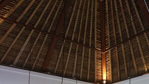 A modern kitchen with wooden cabinets, a dining table, and three hanging wicker pendant lights. - Luxury Villa Stay – Serenity, Style, and Convenience Combined (Badung)