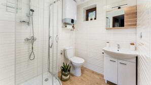 Un baño moderno con cabina de ducha de vidrio, inodoro y lavamanos con encimera de madera.
