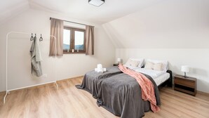 Un dormitorio con cama, mesitas de noche, ventana y luz en el techo.