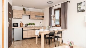 Una cocina moderna con armarios de madera, microondas integrado y una zona de comedor con mesa y sillas.