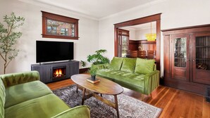 Sala de estar com lareira, sofá verde e televisão.