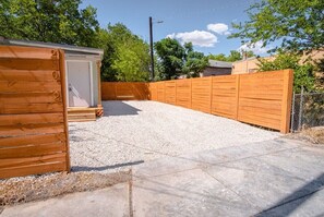 Ein umzäunter Garten mit Kiesfläche und einem Holzschuppen.