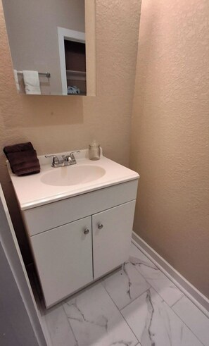 A bathroom with a white sink, a mirror, and a marble floor.