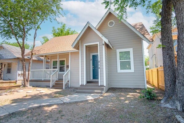 A single-story house with a front porch, a blue door, and a small front yard.