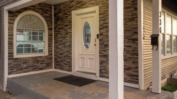 Une maison avec une façade en pierre, une porte blanche et une boîte aux lettres.