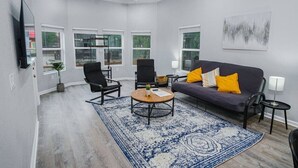A living room with a sofa, two armchairs, a coffee table, and a TV.