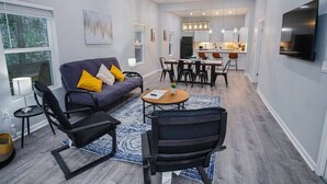 A modern living room with a sofa, chairs, a coffee table, and a dining area with a table and chairs.