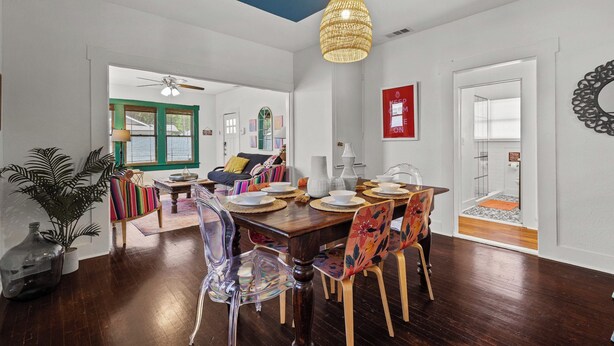 A dining area with a wooden table set for four, clear chairs, and a hanging light fixture. - Gorgeous Artistic Fully Fenced Home Near Downtown (San Antonio)