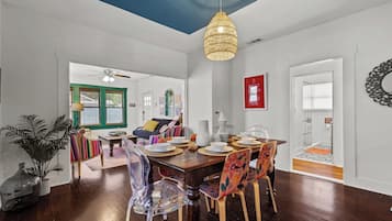 A dining area with a wooden table set for four, clear chairs, and a hanging light fixture.