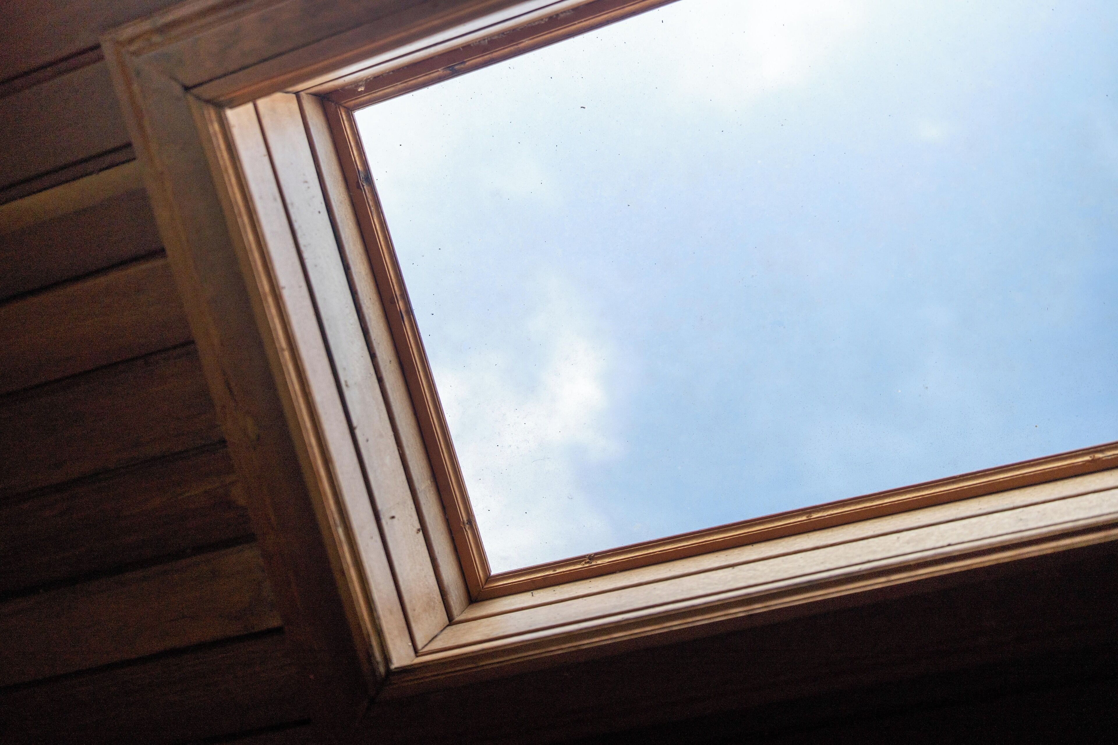 A skylight with a wooden frame and a clear view of the sky.