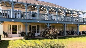 A two-story building with a covered patio area, outdoor seating, and a small garden. - 2-room Apartment for 7 People - Comfort (Argentat-sur-Dordogne)