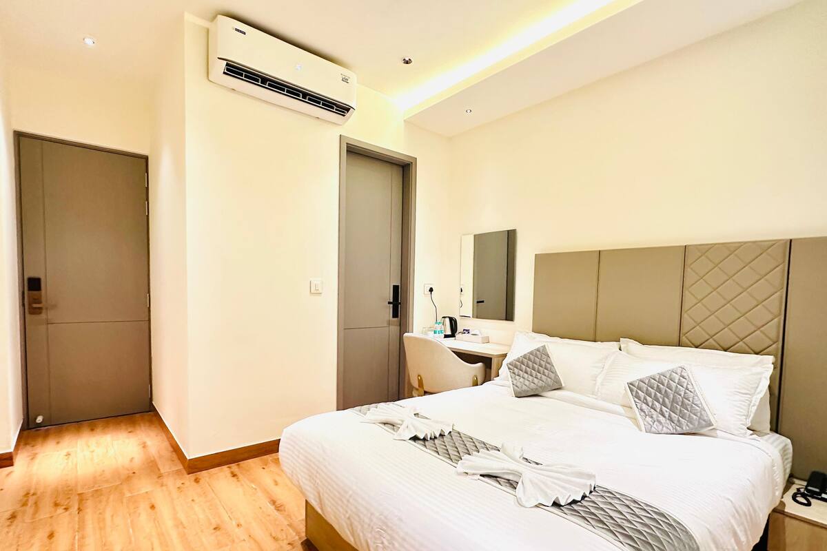 A hotel room with a bed, bedside table, desk, and a mirror.