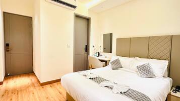 A hotel room with a bed, bedside table, desk, and a mirror.