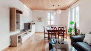 A modern living room with a wooden ceiling, a dining area with a glass table, and a black sofa. - Close to the Center of Lugano (Sestante 2) (Viganello)
