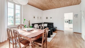 A modern living room with a dining table, black leather sofa, and a wooden ceiling. - Close to the Center of Lugano (Sestante 2) (Viganello)
