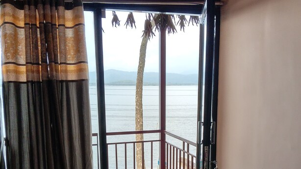 Ein offener Balkon mit Blick auf ein Gewässer und einen Baum.