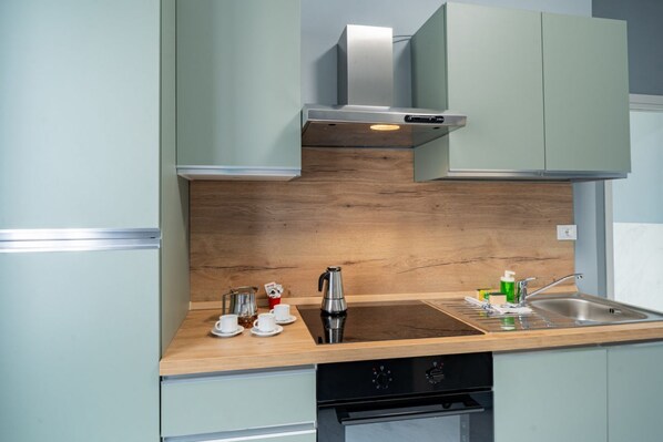 A modern kitchen with a wooden countertop, stainless steel appliances, and light-colored cabinetry.