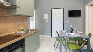 Et lille køkken med træbordplade, indbygget komfur og spiseplads med bord dækket til fire personer.