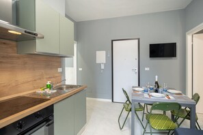 A compact kitchen with a wooden countertop, a built-in stove, and a dining area with a table set for four.
