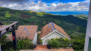 Une maison avec un toit de chaume, une terrasse en bois et une vue sur des collines ondoyantes.