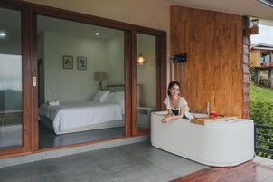 Une chambre moderne avec un lit, un comptoir d’accueil en bois et une grande fenêtre.