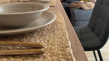 A dining table set with plates and a glass, a woven placemat, and a chair.