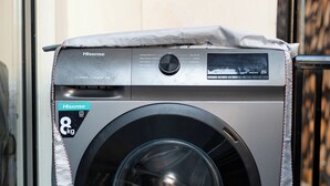 A compact Hisense washing machine with a stainless steel finish, located indoors with a tiled floor.