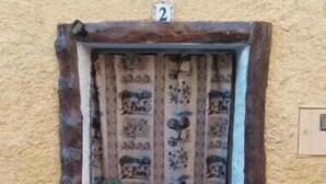 A rustic door with a number '2' above it, set in a textured wall.
