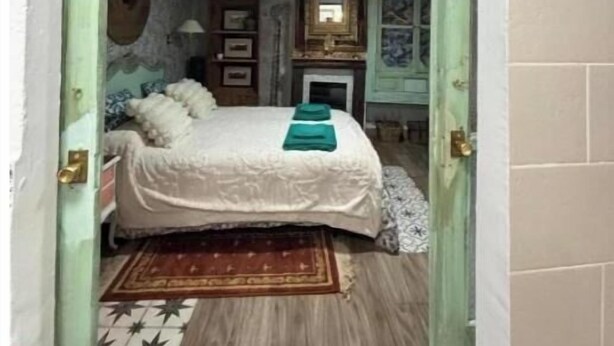 A bedroom with a bed, a nightstand, a dresser, a mirror, and a window.