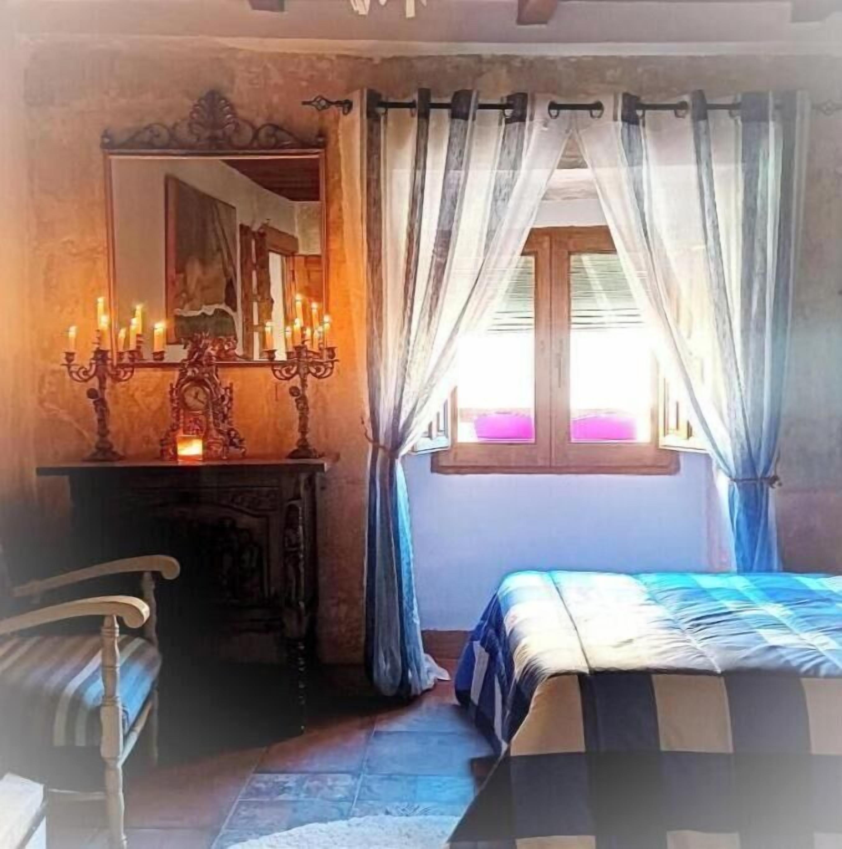 Un dormitorio con cama, cómoda, espejo y ventana con cortinas.