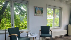 Ett rum med två grönklädda fåtöljer, ett litet vitt bord och ett element.