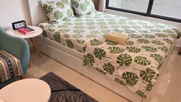 Une chambre à coucher bien rangée, avec un lit, une petite table ronde et une chaise.