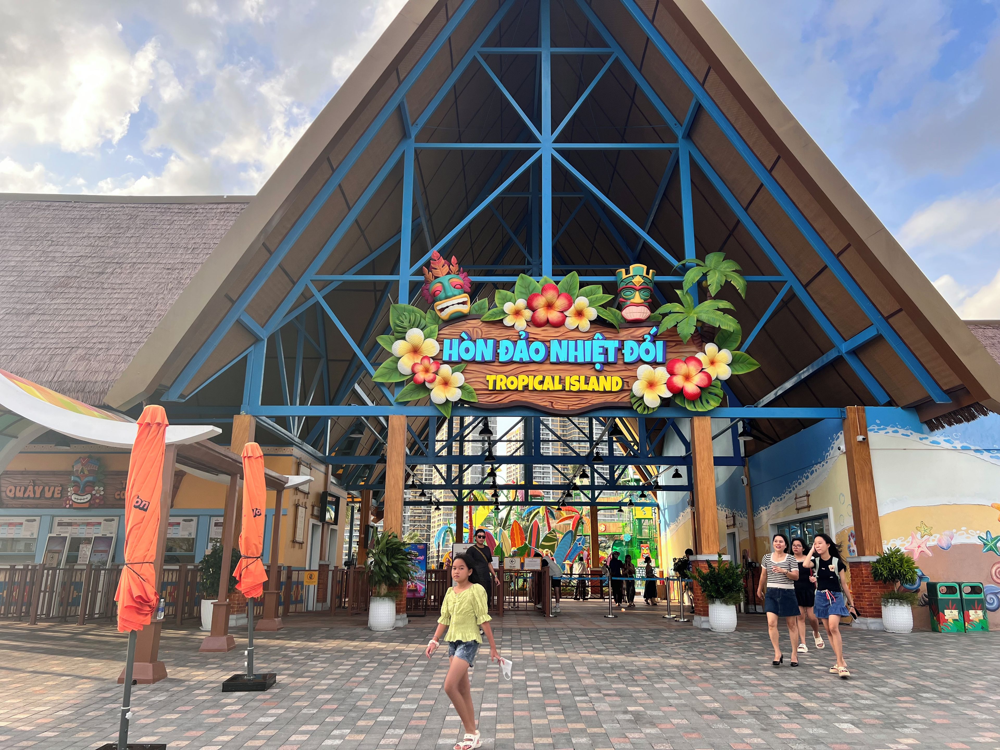 A tropical-themed entrance with a sign reading "Hòn Đảo Nghệ Độ Tropical Island".
