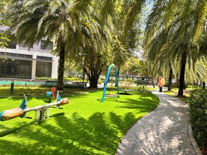 A park with a playground, a walking path, and a building in the background. - Vinhome Grand Park Homestay-HappyStay (Ho Chi Minh City)