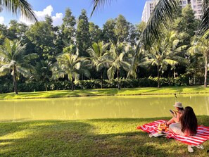 A park with a pond, grass, and palm trees. - Vinhome Grand Park Homestay-HappyStay (Ho Chi Minh City)
