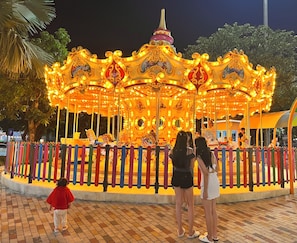 Un carrousel agrémenté de décorations et de lumières raffinées, entouré d’une clôture aux couleurs vives.