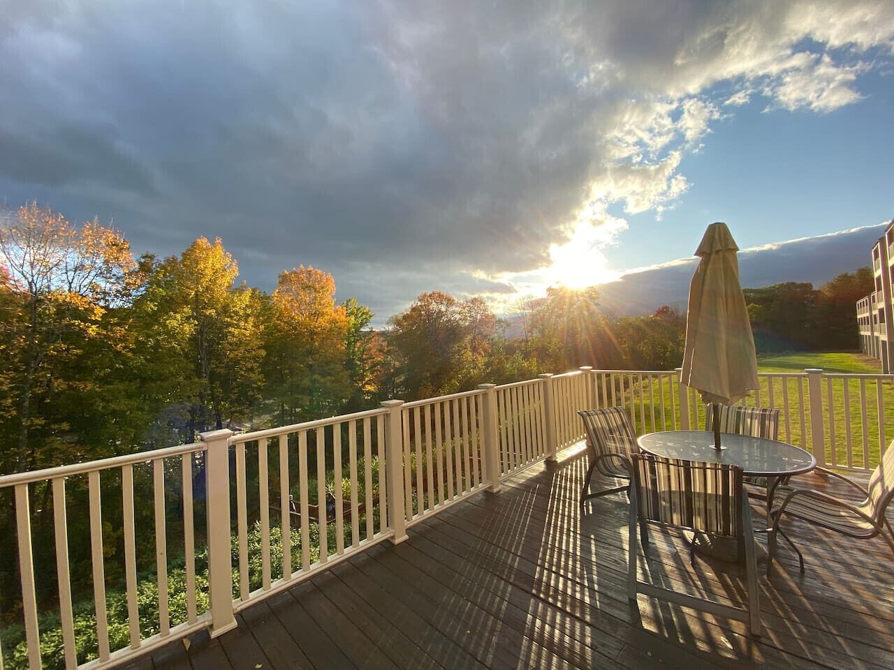 A wooden deck with a white railing, a round table, and two chairs.